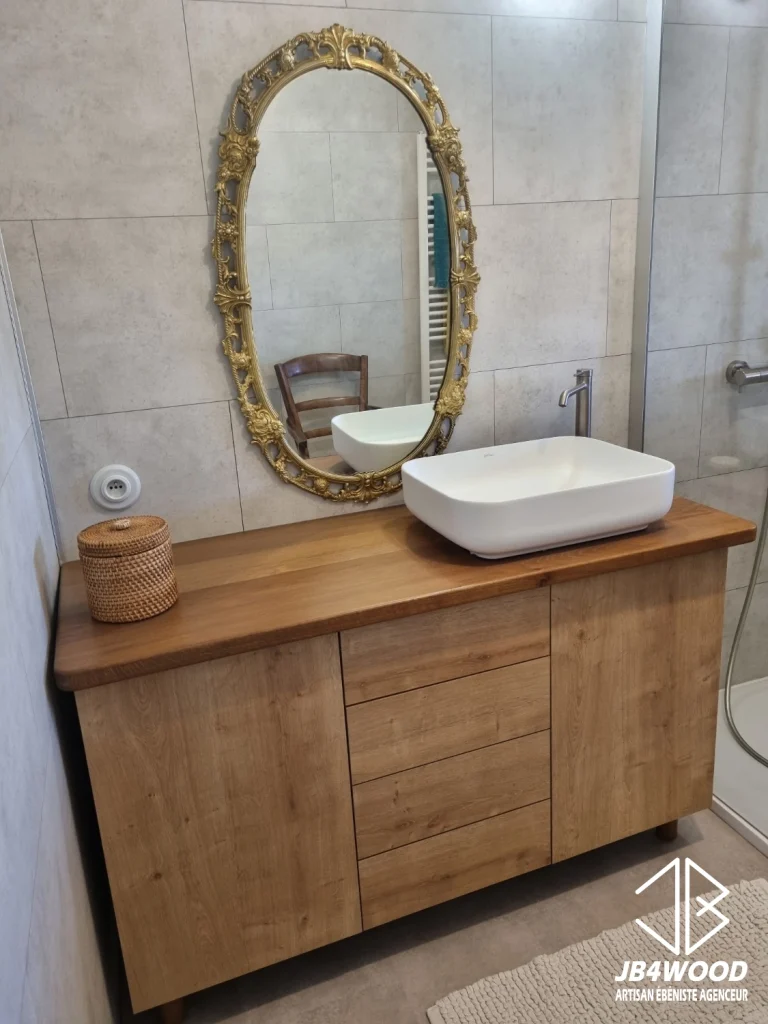 Meuble de salle de bain sur mesure avec plan de travail et piètement en chêne massif teinté. Les coins arrondis et l'aspect général du meuble veulent donner un effet de meuble mobile pour respecter la cohérence avec la décoration de la maison.