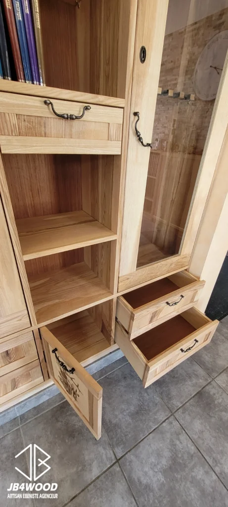 Réalisation d'une armoire en bois de frêne pour ranger des fusils et du matériel de chasse. Elle a été réalisé sur mesure avec des portes vitrées à fermeture à clé. Une gravure de sanglier a été incorporée en partie basse de l'ouvrage.
